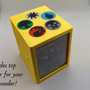 May include: Yellow cube-shaped card box with a clear window on one side. The top of the box has five colored circles with symbols representing the five elements of magic: fire, water, earth, air, and a skull. The text "Command Tower of All" is visible through the window.