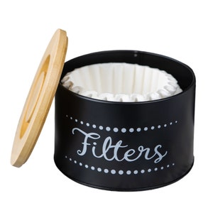 May include: Black metal coffee filter canister with a wooden lid. The canister has a white label that says "Filters" with a dotted border.