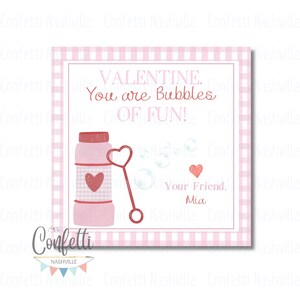 May include: Pink and red Valentine's Day card with a pink gingham background. The card features a pink bottle of bubbles with a red heart on it and a red wand with a heart on the end. The text on the card reads "VALENTINE. You are Bubbles OF FUN!" and "Your Friend. Mia".