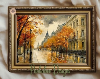 May include: A framed painting depicts a European street scene in autumn. The artwork features a wet street reflecting the buildings and trees with orange and yellow leaves. The frame is gold and the artwork is labeled "Punkaboo Designs."