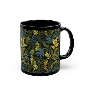 May include: Black ceramic coffee mug featuring a botanical pattern of green, gold, and blue leaves on a black background. The mug has a black handle and a glossy finish. Perfect for hot beverages.