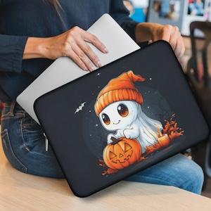 May include: Black laptop sleeve featuring a cartoon ghost wearing an orange beanie and holding a jack-o'-lantern. The design includes a bat, stars, and autumn leaves, perfect for Halloween. The sleeve is designed to fit a laptop.