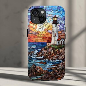 May include: A stained glass style phone case featuring a lighthouse on a rocky shore with a sunset in the background.
