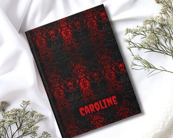 May include: A black and red journal with a lace pattern and the name "CAROLINE" printed in red letters.
