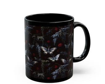 May include: Black ceramic mug featuring a dark, detailed pattern of butterflies, ferns, and red floral accents. The design is set against a black background, creating a striking contrast. The mug has a standard handle for easy gripping.