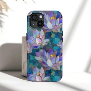 May include: A smartphone case featuring a floral design of blue, purple, and white lotus flowers. The case has a glossy finish and a dark blue camera module. The background is a mosaic of blue and green hues.