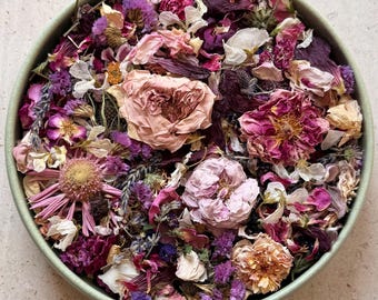 May include: A round, light green container filled with a dense mixture of dried flowers and petals. The assortment includes pink and deep red roses, purple lavender sprigs, yellow-centered echinacea, and various small white and violet blossoms.