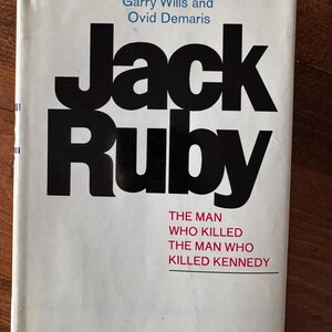 May include: A book cover with the title "Jack Ruby" in large black letters. The author's names, Garry Wills and Ovid Demaris, are above the title. The subtitle reads "The Man Who Killed The Man Who Killed Kennedy."