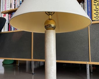 Puede incluir: Una lámpara de mesa color crema con una pantalla blanca. La lámpara tiene una base cilíndrica con un patrón texturizado, una esfera dorada y una base cuadrada. La lámpara mide aproximadamente 76 cm de altura.