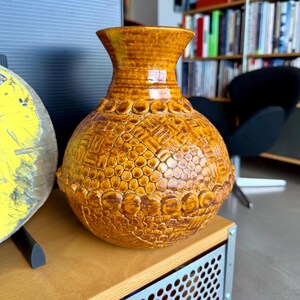 Jarrón de cerámica de estudio moderno, texturizado, de estilo brutalista, color amarillo ocre, con diseño posmoderno táctil.