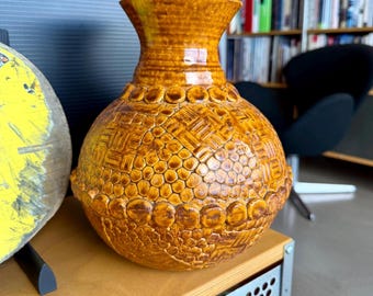 Jarrón de cerámica de estudio moderno, texturizado, de estilo brutalista, color amarillo ocre, con diseño posmoderno táctil.