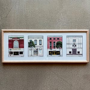 May include: A framed print featuring four architectural illustrations of luxury storefronts. The print includes the Valentino and Cartier boutiques, among others. The artwork is set in a light wood frame and is displayed against a neutral background.
