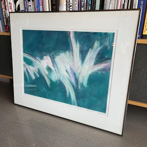Peut inclure: Impression d'art encadrée avec des coups de pinceau blancs et turquoise sur fond turquoise. L'œuvre est présentée dans un passe-partout blanc et un cadre en métal foncé. L'impression est posée sur une surface grise, avec une bibliothèque en arrière-plan.