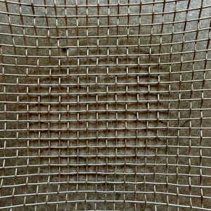 May include: A metallic wire mesh screen featuring a uniform grid pattern of intersecting silver-toned wires. The structure consists of evenly spaced horizontal and vertical strands creating a series of small, square-shaped openings throughout the surface.