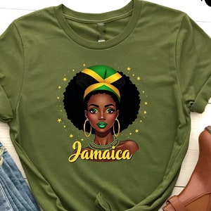 Peut inclure: T-shirt vert avec une illustration noire et brune d'une femme portant un bandeau avec le drapeau jamaïcain. Le texte "Jamaïque" est imprimé sous l'illustration.