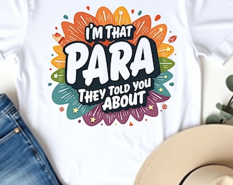 Könnte beinhalten: Weißes T-Shirt mit dem Text "I'M THAT PARA THEY TOLD YOU ABOUT" in einem farbenfrohen Blumendesign. Das Shirt wird mit blauen Jeans und einem beigen Hut kombiniert. Das Wort "White" befindet sich oben links.