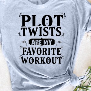 May include: A light blue t-shirt with black text that reads "Plot Twists Are My Favorite Workout".