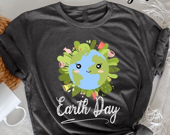 Puede incluir: Camiseta de color gris oscuro jaspeado con una ilustración de dibujos animados de la Tierra con una cara sonriente rodeada de hojas verdes y flores. El texto "Earth Day" está escrito en blanco debajo de la ilustración.