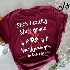 Ella es belleza Ella es gracia Ella te picoteará en la cara Camiseta, Pollo divertido, señora loca del pollo, Gallo de mujer, Camiseta de granjero de gallina,