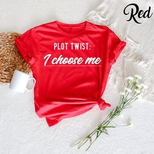 May include: Red t-shirt with the text "PLOT TWIST: I choose me" printed in white.