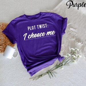 May include: Purple t-shirt with the text "PLOT TWIST: I choose me" in white.