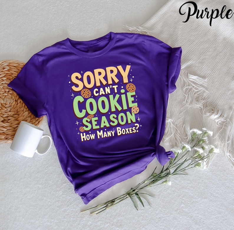 May include: Purple t-shirt with the text "Sorry can't cookie season. How many boxes?" in green and yellow text with cookie images.