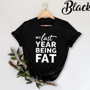 May include: Black t-shirt with white text that reads "My last year being fat".