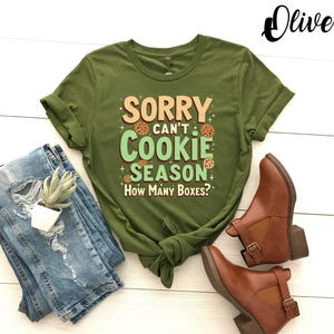 May include: Green t-shirt with the text "Sorry can't cookie season. How many boxes?" in a light green box with brown cookie images.
