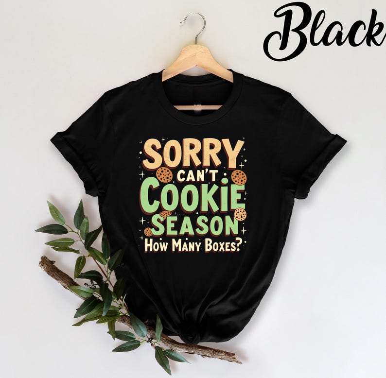 May include: Black t-shirt with a green and white graphic that says "Sorry can't cookie season. How many boxes?" with cookie images.