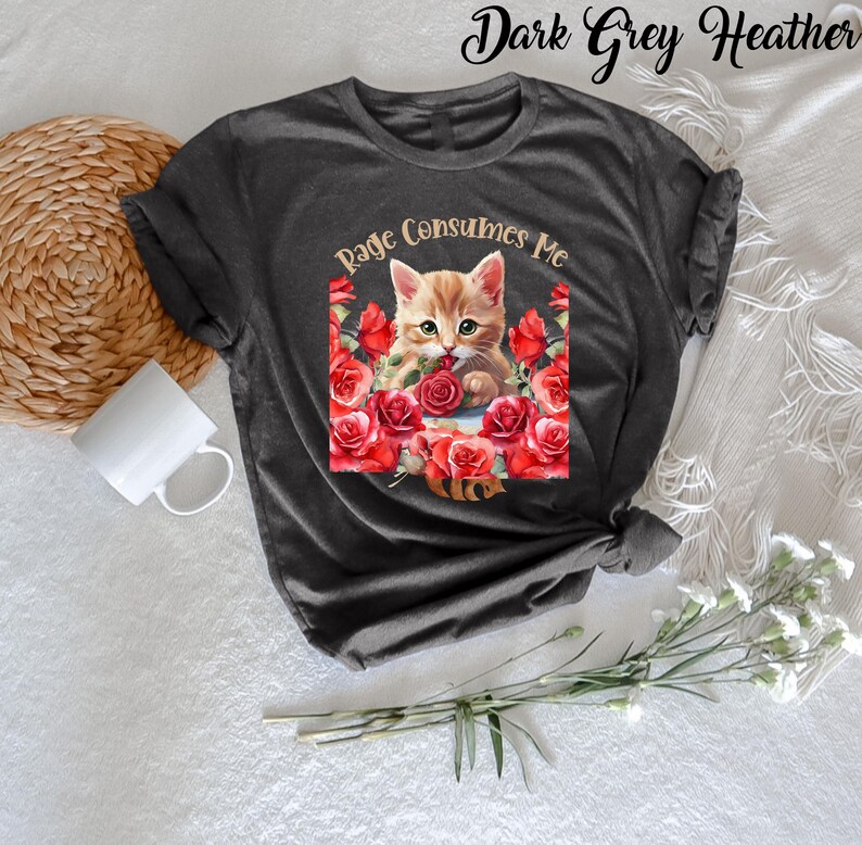 May include: Dark grey heather t-shirt featuring a graphic of a ginger kitten surrounded by red roses, with the text "Rage Consumes Me". The shirt has short sleeves and a crew neck.