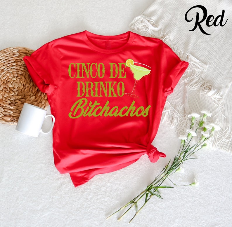 May include: Red t-shirt with the text "Cinco de Drinko Bitchachos" in gold lettering and a green margarita glass graphic.