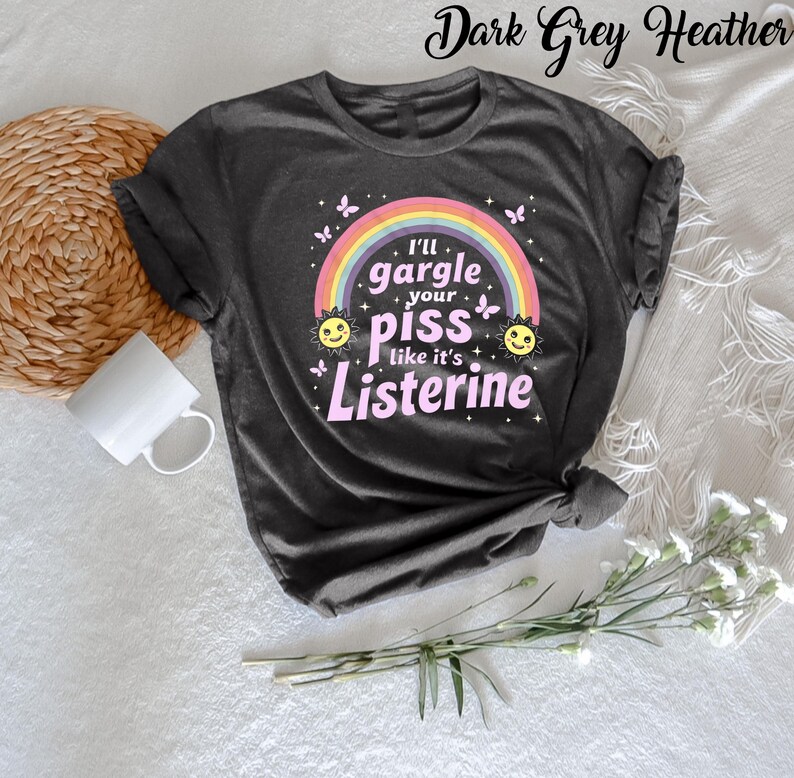 May include: Dark grey heather t-shirt with a rainbow, suns, and butterflies. The text on the shirt reads "I'll gargle your piss like it's Listerine."