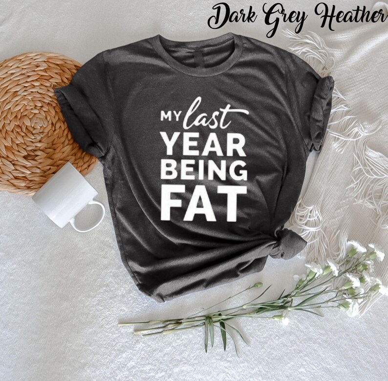 May include: Dark grey heather t-shirt with the text "My last year being fat" in white.