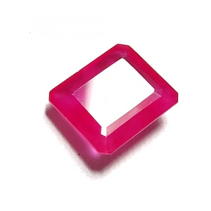 May include: A bright pink gemstone with a square shape and a hollow center.