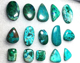 Puede incluir: Una colección de piedras preciosas pulidas en varias formas, incluyendo ovaladas, en forma de lágrima y triangulares. Las piedras muestran una mezcla de tonos turquesa, turquesa y verde oscuro, con patrones y texturas únicos. Las piedras preciosas están dispuestas sobre una superficie blanca.
