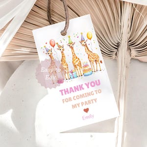 Könnte beinhalten: Ein weißes Geschenk-Etikett mit braunem Band zeigt vier Giraffen mit Partyhüten und Luftballons. Auf dem Etikett steht "Thank You For Coming To My Party" in rosa Schrift, mit einem Herz und dem Namen "Emily" darunter. Ein Kuchen und Geschenke sind ebenfalls abgebildet.