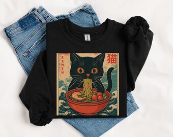 May include: Black sweatshirt featuring a graphic of a black cat eating ramen from a red bowl. The cat has orange eyes and is surrounded by Japanese text and wave patterns. The word "Ramen" is printed vertically on the left.