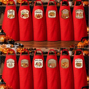 May include: A collection of twelve red aprons, each featuring a unique fall-themed graphic label. The designs include illustrations of caramel apples, apple pie, pumpkins, harvest blessings, apple cider, and hot cocoa with autumn-inspired text.