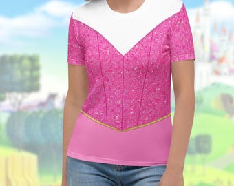 May include: A pink t-shirt with a white neckline and a pink bodice with a glittery texture. The shirt has a gold trim at the waist and short sleeves. The shirt is inspired by a princess costume.