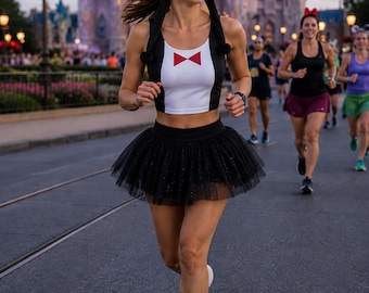 May include: A black and white penguin-themed beanie with ear flaps and a pom-pom, a black and white cropped tank top featuring a red bowtie graphic, a black tulle tutu skirt, and bright yellow athletic running shoes with white soles.