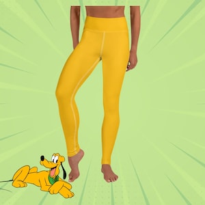 May include: Yellow yoga leggings featuring a cartoon image of Pluto the dog. The leggings are a bright yellow colour and have a high waist.