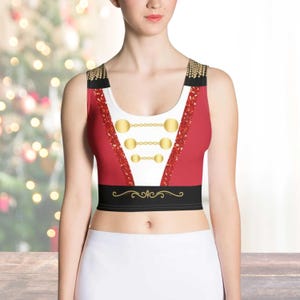 Puede incluir: Top corto rojo y negro con detalles dorados y cuello blanco. El top tiene un diseño que recuerda a un traje de maestro de ceremonias.