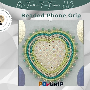 May include: A heart-shaped beaded phone grip with a white center and green and blue beaded trim. The grip is labeled "POPGRIP".