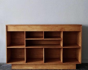 Może przedstawiać: Drewniana półka z wieloma przegródkami. Półka wykonana jest z jasnobrązowego drewna i ma prosty, minimalistyczny design.