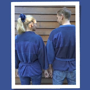 Könnte beinhalten: Zwei Personen tragen passende marineblaue Kimono-Roben mit strukturiertem Design und passenden Gürteln. Sie halten Händchen. Der Hintergrund ist eine Holzwand.