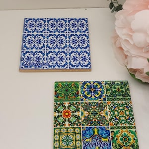 Puede incluir: Dos posavasos cuadrados de cerámica con diseños de azulejos portugueses. Uno presenta un patrón floral azul y blanco, el otro un mosaico colorido de motivos florales. Ambos tienen la palabra "Portugal" impresa.