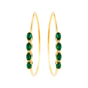 May include: A pair of gold hoop earrings featuring four oval-cut green gemstones and three small clear accent stones set in a vertical row along the front of each thin, circular gold band, creating a symmetrical and elegant jewelry design.