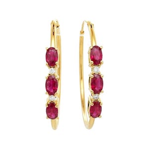 May include: A pair of gold hoop earrings. Each earring features three oval-cut, deep red rubies and small, round, clear diamonds. The earrings are set in a polished gold metal, creating a classic and elegant look. The rubies are a vibrant, eye-catching color.