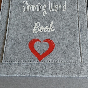 May include: Gray felt pouch with white embroidery that reads "Natasha's Slimming World Book" and a red heart.