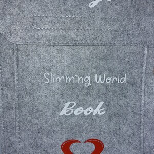 May include: A gray felt book bag with the text "Janay's Slimming World Book" and a red heart.